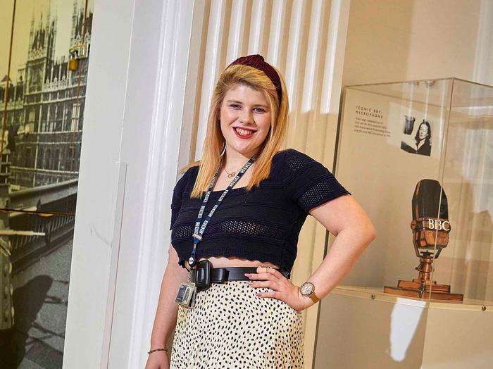 A smiling young female is standing in a corridor