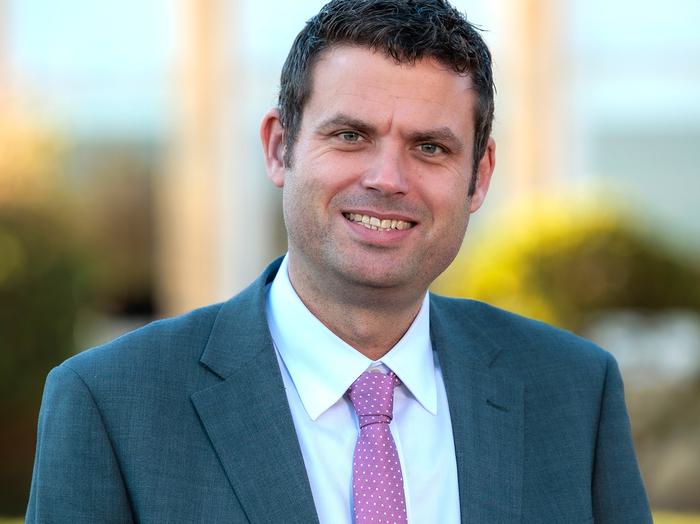 A head and shoulder portrait of an adult male in a suit