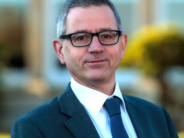 A head and shoulder portrait of an adult male in a suit
