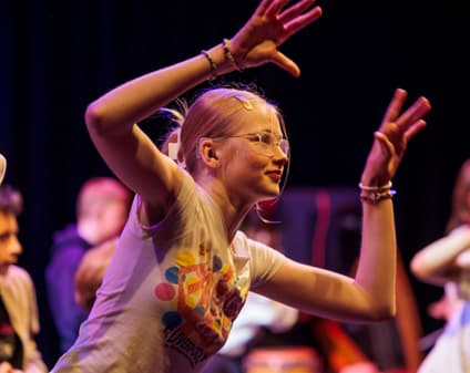 A dancing action shot of a group of students with a focus on a female student