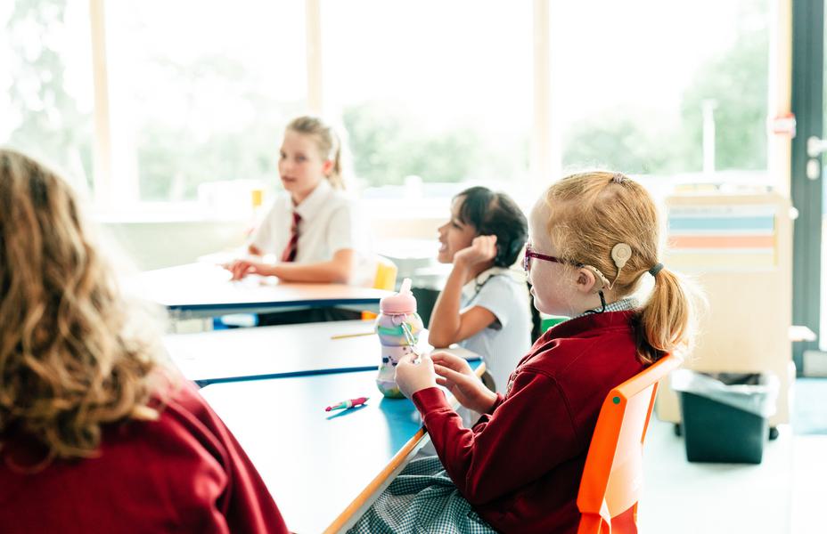 Primary children in their classroom sitting at their desks.