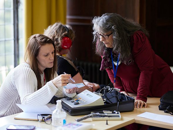 Some sitting at a desk is showing another person a document she is working on