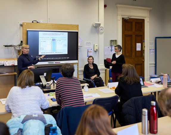 Adults in a training room looking at a screen with the lecturer
