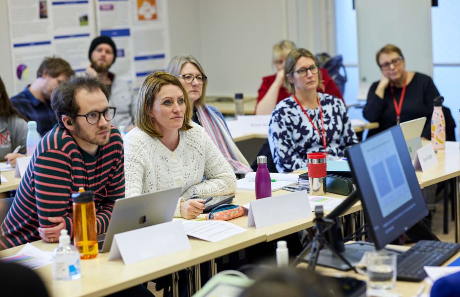 Adult students are sitting at desks in a lecture.
