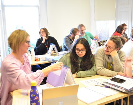 A group of mature students sitting at desks looking at their work.