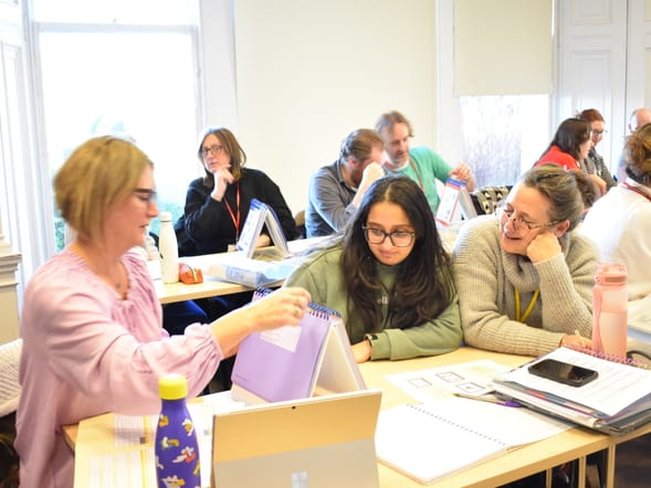 A group of mature students sitting at desks looking at their work.