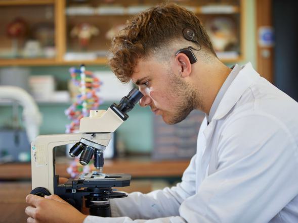 A young male is looking through a microscope