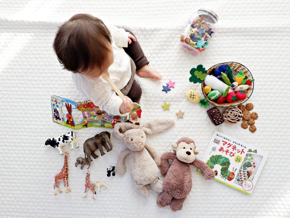 A young child is surrounded by toys and is seen from above