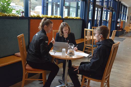 A photo of two adults interviewing a pupil