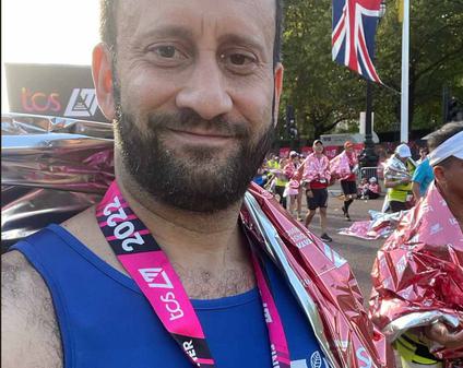 A close up of a male in running wear with the London Marathon medal around his neck.