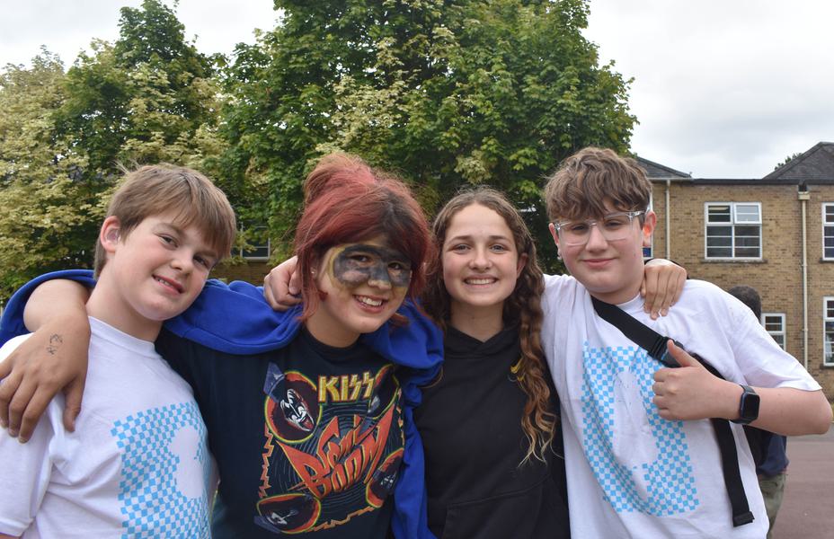 A group of young students are smiling with their arms around each other