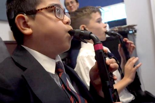 Two young male students are playing saxophones