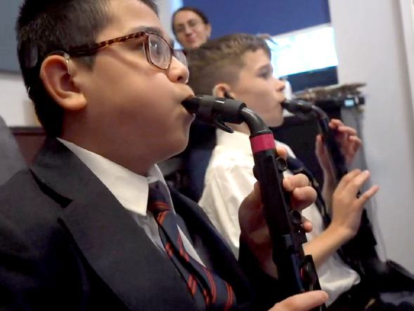 Two young male students are playing saxophones