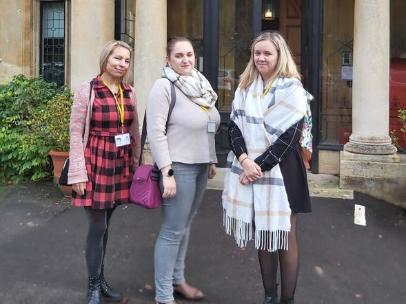 Three adult females are standing in front of a building.