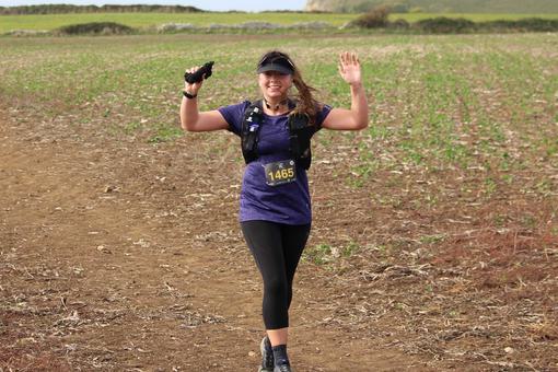 A female runner is waving in the countryside