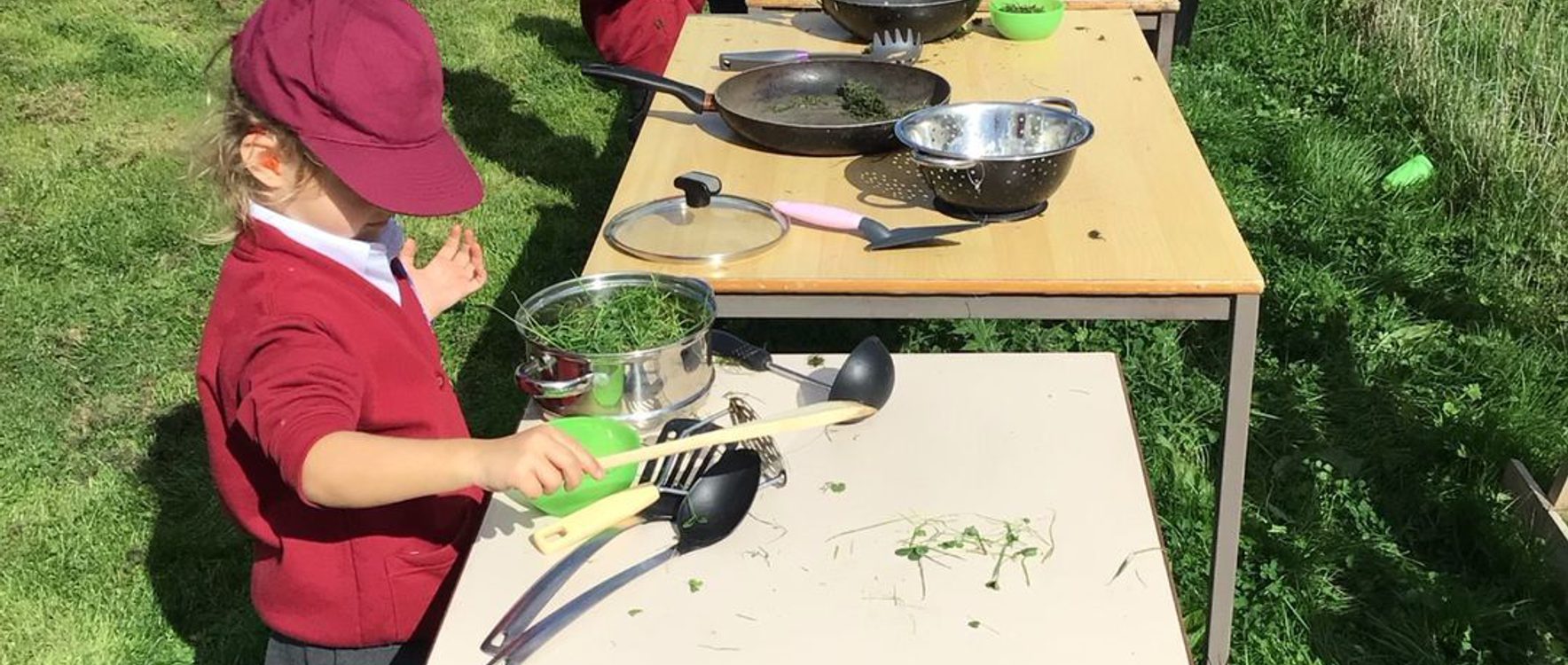Young children cooking at tables outside